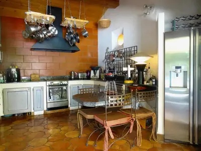 a kitchen with a table and a refrigerator at Mas D'Ange en Provence in Les Taillades