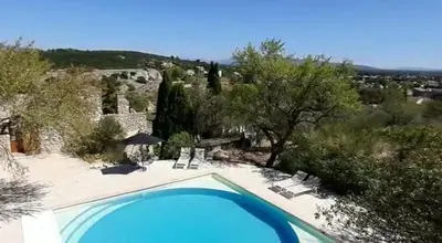 a large blue swimming pool with chairs and trees at Le Fort de Bramafan in Caumont-sur-Durance