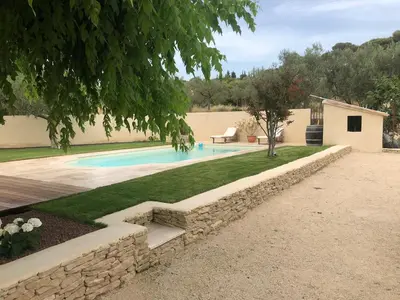 a swimming pool in a yard with a stone wall at Gîte ,studio dans le village de lagnes in Lagnes