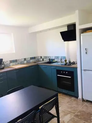 a kitchen with blue cabinets and a table with chairs at Gîte ,studio dans le village de lagnes in Lagnes