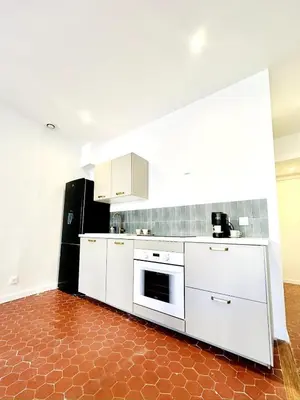 a kitchen with white cabinets and a red tile floor at Design and Provençal Elegance Suite in Aix in Aix-en-Provence