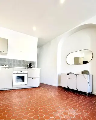 a kitchen with white cabinets and a red tile floor at Design and Provençal Elegance Suite in Aix in Aix-en-Provence