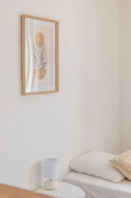 a picture on a wall above a bed with a lamp at Appartement confortable L'Éclat Doré in Pertuis