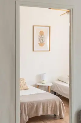 a white room with two beds and a table at Appartement confortable L'Éclat Doré in Pertuis