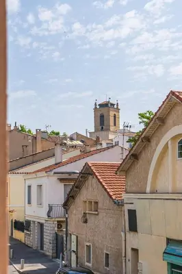 a group of buildings with a clock tower at Appartement confortable L'Éclat Doré in Pertuis