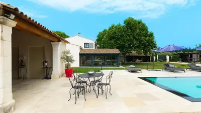 a patio with a table and chairs next to a pool at Mas Provençal chic et élégant - Alpilles et Luberon in Sénas