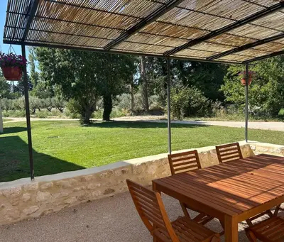 a wooden table and chairs under a pergola at Le Jas de la Cascade in Les Vignères