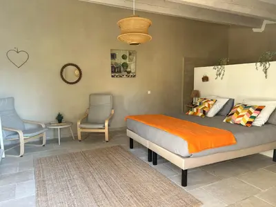 a bedroom with a bed and two chairs and a clock at Le Jas de la Cascade in Les Vignères