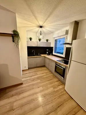 a kitchen with a white refrigerator and wooden floors at Suite appartement in Châteaurenard