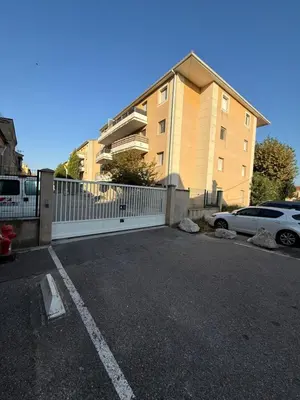 a parking lot with a white fence and a building at Suite appartement in Châteaurenard