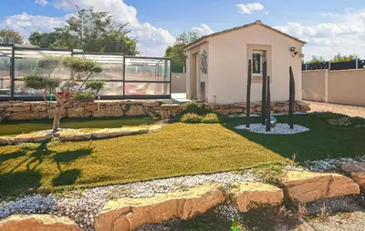 a house with a stone wall in front of a yard at Villa Avec Piscine Privée in Carpentras
