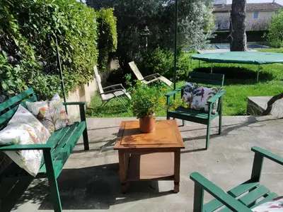 a patio with two green chairs and a table with a potted plant at Vaste villa , piscine , garage pour vélos et motos , grand parking in Caromb