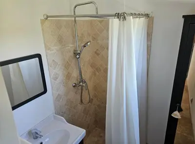 a bathroom with a shower curtain and a sink at Les oliviers in Saint-Didier