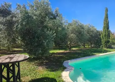 a wooden picnic table next to a swimming pool at Les oliviers in Saint-Didier