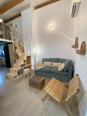 a living room with a blue couch and wooden stairs at L appartement Lambescain in Lambesc