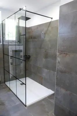a glass shower in a room with a wall at Villa Au Coeur Du Luberon in Maubec