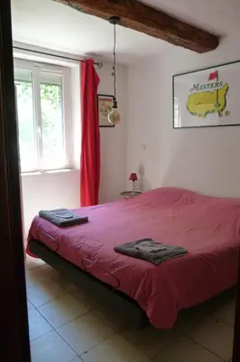a bedroom with a red bed and a window at Villa Au Coeur Du Luberon in Maubec