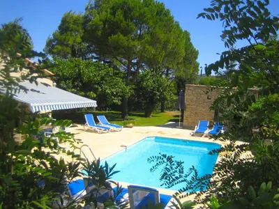 a swimming pool with blue lounge chairs and trees at Attractive Holiday Home in C reste with Pool in Céreste