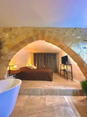 a master bedroom with a bed and a stone wall at Luxe & Volupté sous les Voûtes d'Aix centre ville in Aix-en-Provence