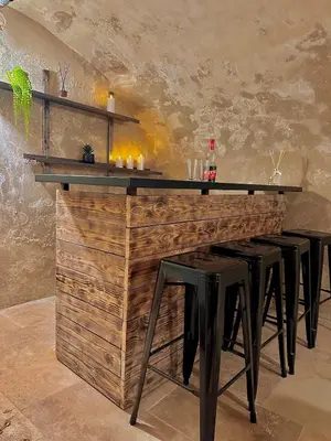 a bar with black stools and a wooden wall at Luxe & Volupté sous les Voûtes d'Aix centre ville in Aix-en-Provence