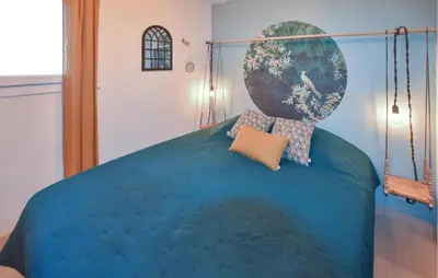 a bedroom with a large bed with a blue comforter at Maisonnette Avec Jacuzzi in Mazan
