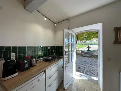 a kitchen with a counter and an open door at Maison des Fontaines - Terrasse & vue sur vignoble, proche Aix-en-Provence 5 personnes - Domaine Viticole Château de Barbebelle, Rognes, Provence in Rognes