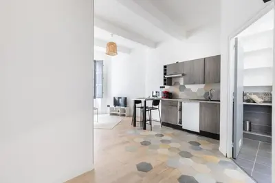a kitchen with white walls and wooden cabinets at Le Rimbaud - Studio moderne en hypercentre - WiFi in Carpentras