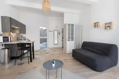 a living room with a black couch and a table at Le Rimbaud - Studio moderne en hypercentre - WiFi in Carpentras