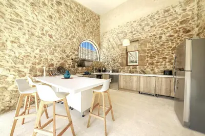 a kitchen with stone walls and a white table and chairs at Historic Mansion In Provence Vineyards in La Tour-dʼAigues