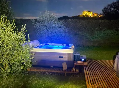 a hot tub sitting on a deck in a yard at night at Tiny House avec vue sur le rocher de Saignon, Luberon in Saignon