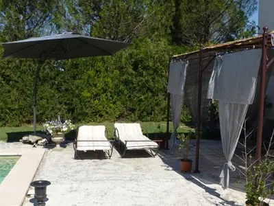 a patio with two chairs and an umbrella at Les Anges in LʼIsle-sur-la-Sorgue