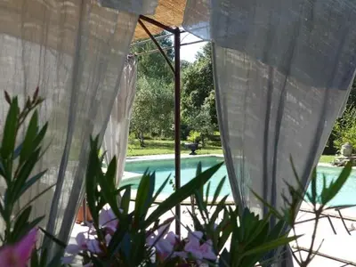 a white curtain in front of a swimming pool at Les Anges in LʼIsle-sur-la-Sorgue