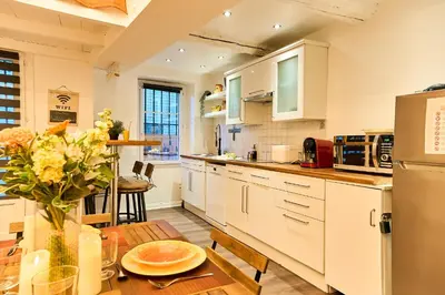 a kitchen with white cabinets and a wooden table at Evasion au centre d Aix loft chic et cosy in Aix-en-Provence