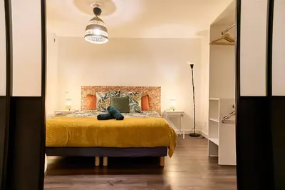 a bedroom with a large bed with a yellow blanket at Evasion au centre d Aix loft chic et cosy in Aix-en-Provence
