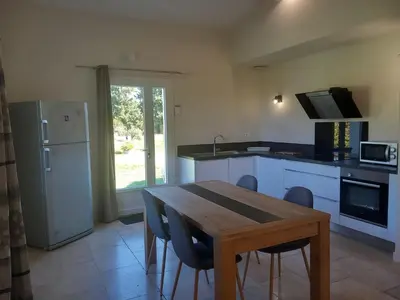 a kitchen with a wooden table and a refrigerator at Les lauriers in Aubignan