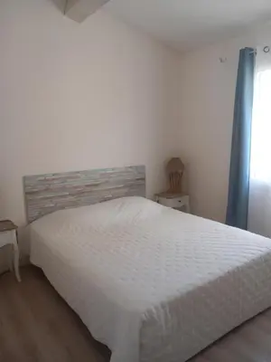 a bedroom with a white bed and a window at Les lauriers in Aubignan