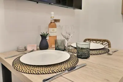 a table with plates and glasses and a bottle of wine at La Parenthèse Aixoise - 3 stars - Parking - Clim in Aix-en-Provence