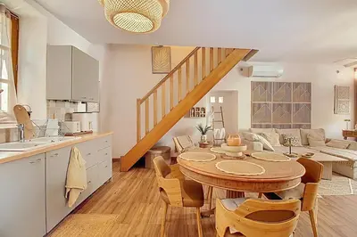 a kitchen and living room with a wooden table and a kitchen and stairs at La Cour de Pétrarque in Fontaine-de-Vaucluse