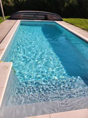 a swimming pool with blue water in a backyard at Tiny House T1 in Entraigues-sur-la-Sorgue