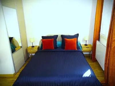 a bedroom with a blue bed with orange and blue pillows at AQUA TERRA-Studio Cozy-Aix Historic Center- SMART TV-WIFI in Aix-en-Provence
