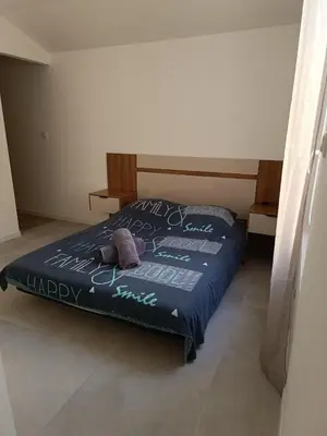 a bed with a blue comforter with a happy mattress at La Villa des Trois in Cavaillon