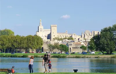a group of people standing near a river with a large building at 4 Bedroom Cozy Home In Eygalières in Eygalières