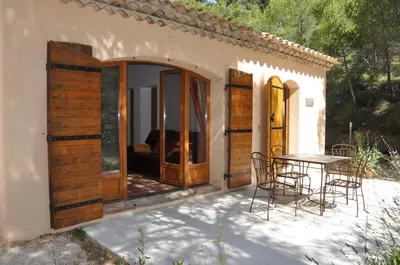 a patio with wooden doors and a table and chairs at Domaine la Garenne in Saint-Marc-Jaumegarde