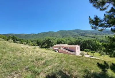 a house on a hill with mountains in the background at Domaine de Battarel, 4 hectares en Luberon in Saint-Martin-de-Castillon