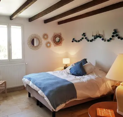 a bedroom with a large bed with blue pillows at Domaine de Battarel, 4 hectares en Luberon in Saint-Martin-de-Castillon