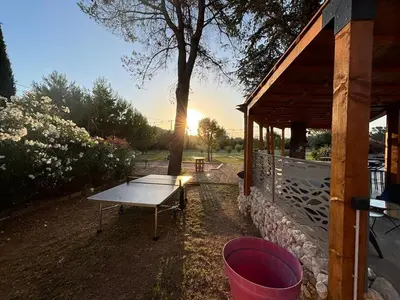 a picnic table next to a building with a tree at Villa Soleil Piscine Jacuzzi Pétanque Espace bbq billard et salons extérieurs in Aix-en-Provence