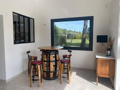 a bar with stools in a room with a window at Villa Soleil Piscine Jacuzzi Pétanque Espace bbq billard et salons extérieurs in Aix-en-Provence