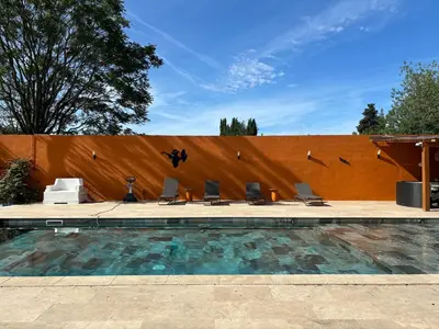 a pool with chairs and birds flying over a fence at Villa Soleil Piscine Jacuzzi Pétanque Espace bbq billard et salons extérieurs in Aix-en-Provence