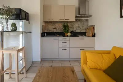 a living room with a couch and a kitchen at La Colline - Pause Provençale in LʼIsle-sur-la-Sorgue