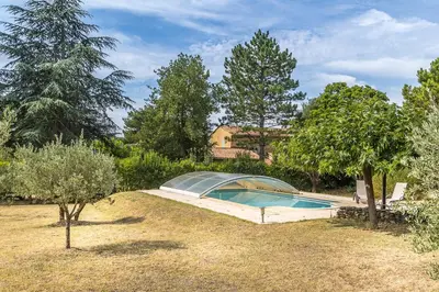 a swimming pool in a yard with trees and a house at La Colline - Pause Provençale in LʼIsle-sur-la-Sorgue